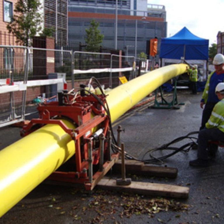 Construction site featuring a large yellow gas  pipe being installed with workers nearby.